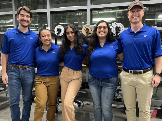 Five students stand in an engineering lab