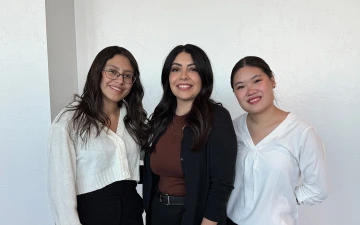Three women with brown hair pose for a photo.