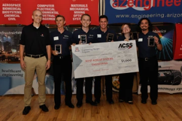 Team 16022 University students with presenter giving them a large award check