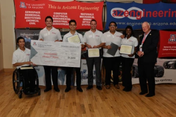 Team 16055 University students with presenter giving them a large award check