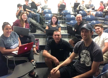 Team 17004 A group of seven university students in a classroom setting, four of which have laptops